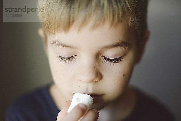 Nahaufnahme eines Jungen mit geschlossenen Augen beim Marshmallow-Essen zu Hause