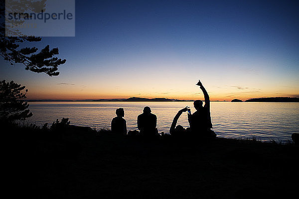 Silhouetten-Männer genießen auf der Insel Sucia gegen den Himmel bei Sonnenuntergang