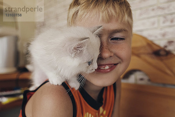 Seitenansicht eines glücklichen Jungen mit Katze auf der Schulter