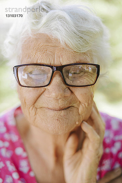 Nahaufnahme einer lächelnden älteren Frau mit Brille im Hinterhof