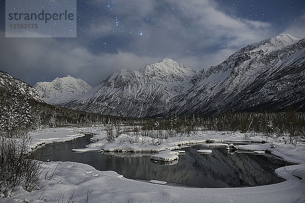 Blick auf den zugefrorenen See bei schneebedecktem Berg vor bewölktem Himmel