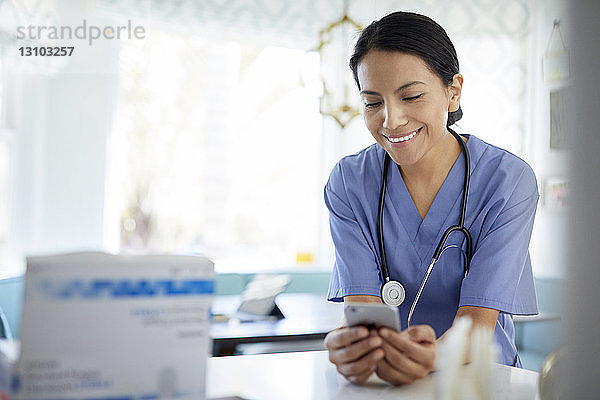 Lächelnde Ärztin mit Smartphone bei der Arbeit im Krankenhaus
