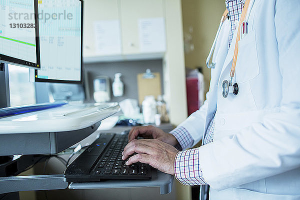 Mittelsektion eines männlichen Arztes am Desktop-Computer auf der Krankenhausstation