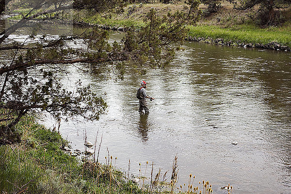 Hochwinkelaufnahme eines erwachsenen Mannes  der im Fluss fischt