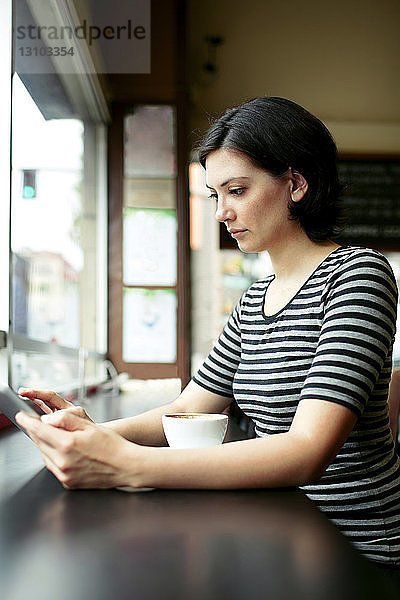 Junge Frau benutzt Tablet-Computer am Café-Tisch