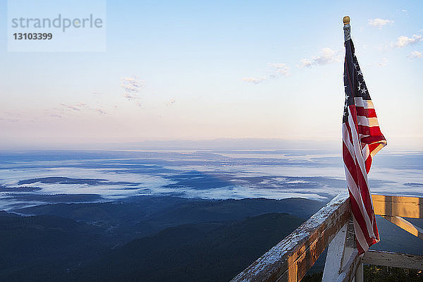 Amerikanische Flagge auf dem Geländer des Feuerwachturms gegen die Landschaft