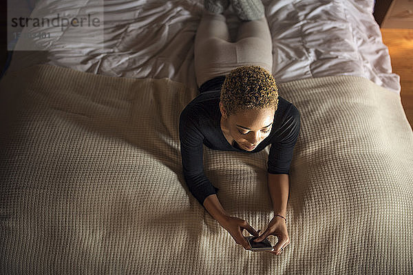 Draufsicht einer Frau  die ein Smartphone am Bett benutzt