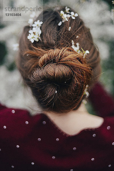 Rückansicht einer Frau mit Blumen auf dem Haar im Park