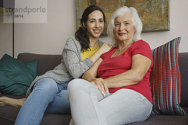Porträt lächelnd ältere Mutter sitzt mit Tochter auf Sofa im Wohnzimmer