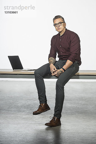 Porträt eines Mannes am Schreibtisch sitzend mit Laptop