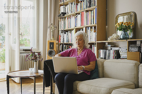 Ältere Frau mit Laptop auf dem Wohnzimmersofa