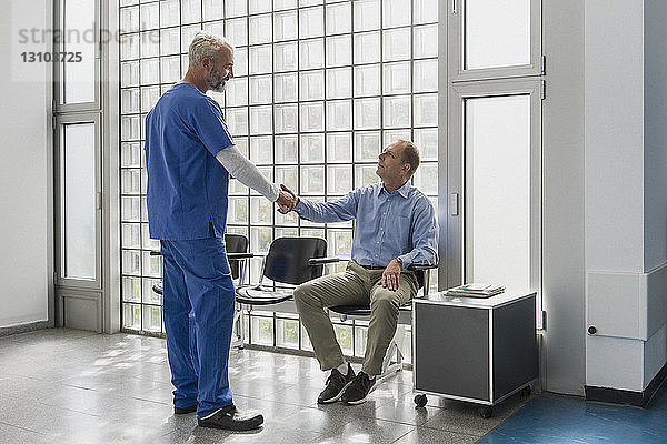 Begrüßung eines Arztes und Händeschütteln mit einem Patienten im Wartezimmer einer Klinik