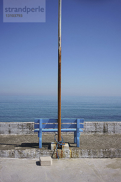 Verrosteter Fahnenmast und blaue Bank mit malerischem Meerblick  Kalyves  Kreta  Griechenland