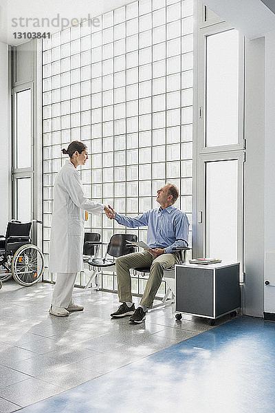 Begrüßung eines Arztes und Händeschütteln mit einem Patienten im Wartezimmer einer Klinik