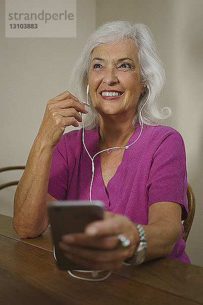 Lächelnde ältere Frau  die mit Kopfhörern und mp3-Player Musik hört