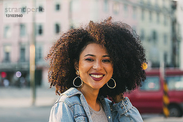 Porträt lächelnde  selbstbewusste junge Frau auf städtischer Straße