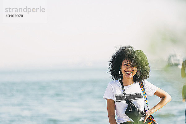 Porträt lächelnde junge Frau am Meeresufer