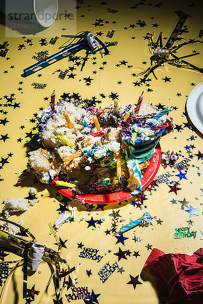 Chaotische Geburtstagstorte und Konfetti auf gelbem Hintergrund