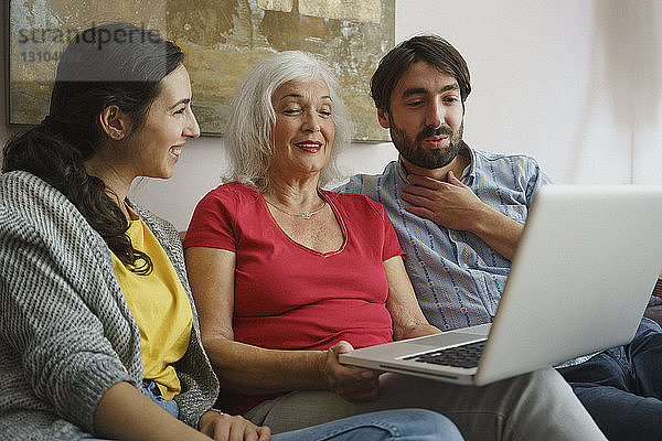 Ältere Mutter benutzt Laptop mit Tochter und Sohn auf dem Wohnzimmersofa