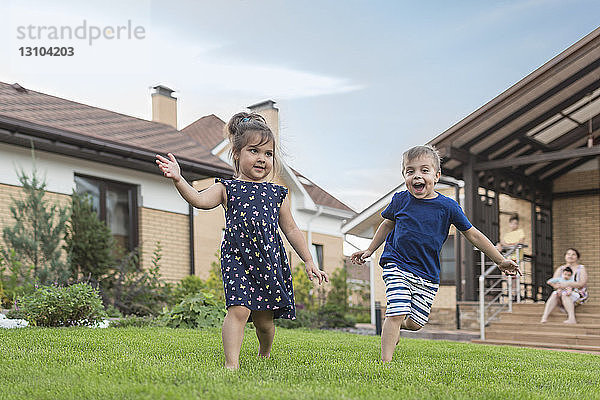 Bruder und Schwester rennen  spielen im Gras im Hinterhof