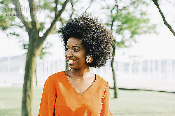 Selbstbewusste  lächelnde junge Frau im sonnigen Park