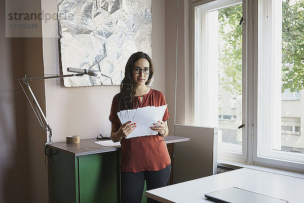 Porträt selbstbewusste Geschäftsfrau mit Papierkram im Büro