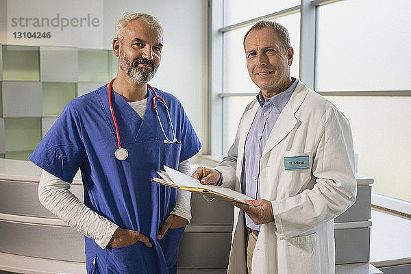 Portrait selbstbewusster männlicher Arzt mit Krankenakte im Krankenhaus