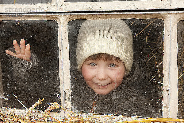 Portrait süßes Mädchen mit Strickmütze am Fenster