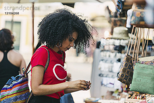 Junge Frau kauft Schmuck an einem Marktstand