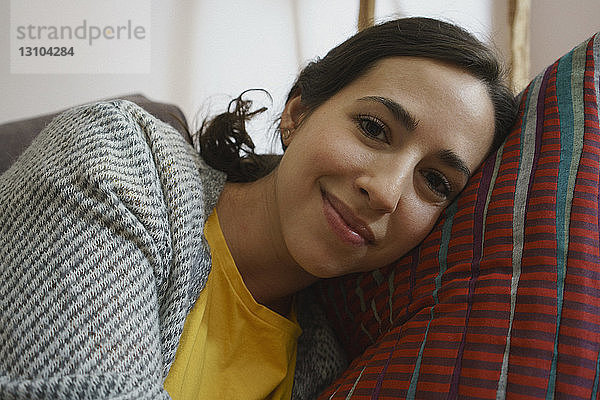 Porträt einer lächelnden Frau  die sich entspannt und auf einem Kissen liegt