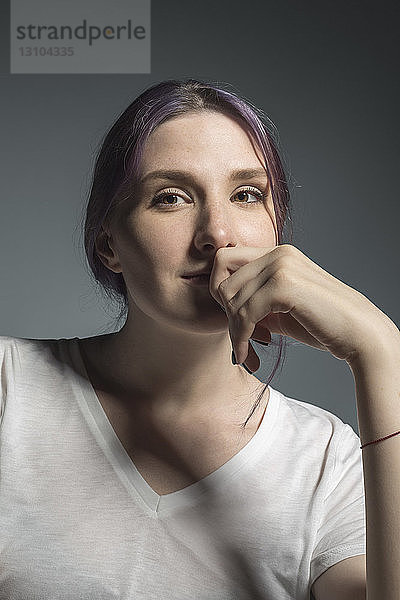 Porträt selbstbewusste junge Frau vor grauem Hintergrund