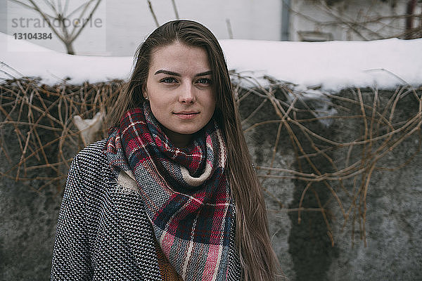 Porträt einer jungen Frau mit kariertem Schal vor einer schneebedeckten Wand