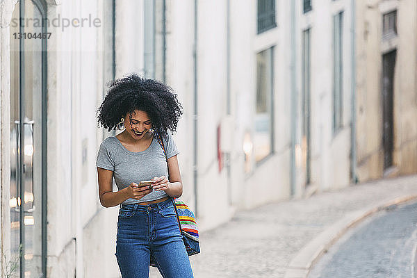 Junge Frau benutzt ihr Smartphone auf einer städtischen Straße