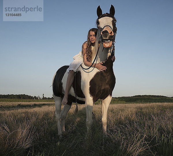 Porträt eines Mädchens  das auf einem Pferd in einem ländlichen Feld liegt