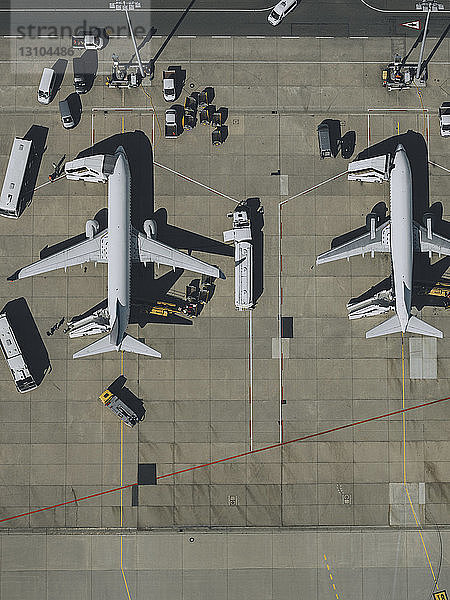 Blick von oben auf Verkehrsflugzeuge  die auf dem Rollfeld eines Flughafens gewartet und vorbereitet werden