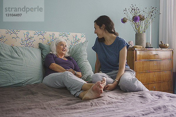 Ältere Mutter im Gespräch mit Tochter auf dem Bett