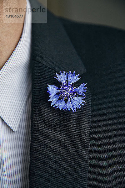 Blaue Blumennadel am Revers eines Mannes