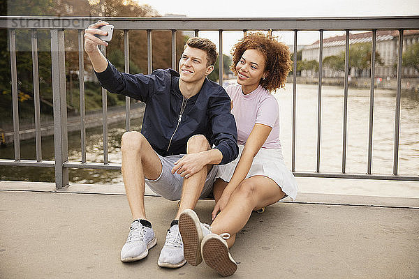 Junges Paar nimmt Selfie mit Kamera-Handy auf städtischen Brücke