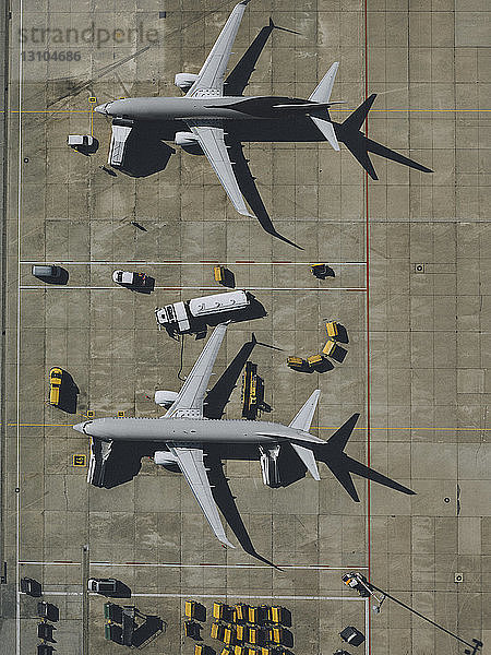 Blick von oben auf ein Verkehrsflugzeug  das auf dem Rollfeld eines Flughafens gewartet und vorbereitet wird