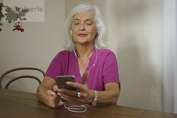 Ältere Frau  die mit Kopfhörern und mp3-Player Musik hört