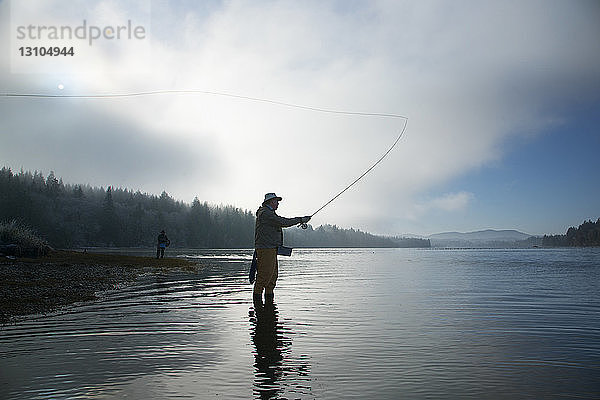 Silhouette eines Fischers beim Fliegenfischen auf Lachs und Cutthroat-Forelle