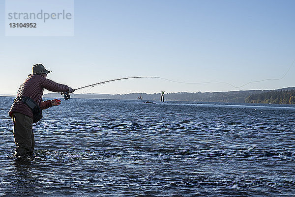 Ein kaukasischer männlicher Fliegenfischer wirft im Salzwasser vor Indian Island im Nordwesten des Bundesstaates Washington  USA  auf Cutthroat-Forelle und Lachs.