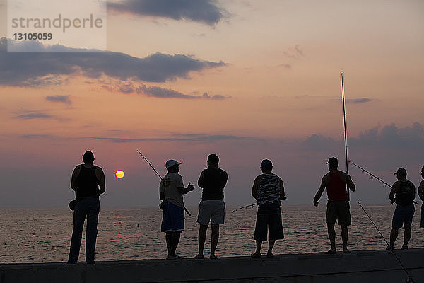 Fischer versuchen ihr Glück und stehen auf dem Geländer der Malecon-Hafenmauer in Havanna  Kuba