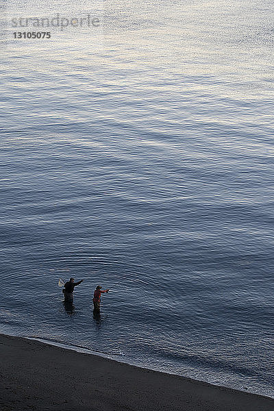 Blick von oben auf einen Führer und einen Fliegenfischer am Wasser  der an einem Strand an der Nordwestküste der USA Lachs- und Meerforellen fängt.