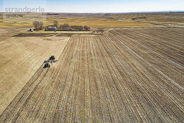 Luftaufnahme eines Traktors  der eine pneumatische Sämaschine zieht und ein Feld sät; Beiseker  Alberta  Kanada