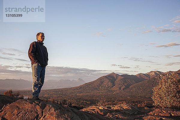 Mann betrachtet die Landschaft vom Gipfel der Butte  Lazy Mountain im Hintergrund an einem klaren  sonnigen Abend im Herbst  Süd-Zentral-Alaska; Palmer  Alaska  Vereinigte Staaten von Amerika