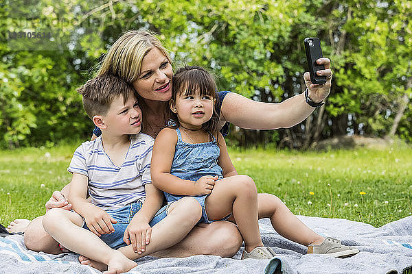 Eine junge Mutter nimmt ein Selbstporträt mit ihrem Sohn und ihrer Tochter in einem Park auf; Edmonton  Alberta  Kanada