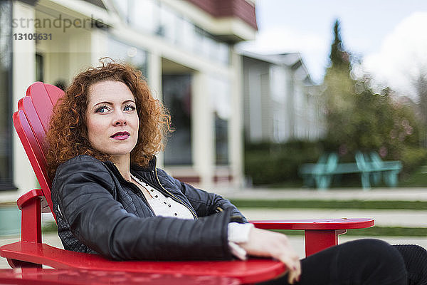 Porträt einer Frau mit rotem  lockigem Haar  die im Frühling im Freien sitzt; North Vancouver  British Columbia  Kanada