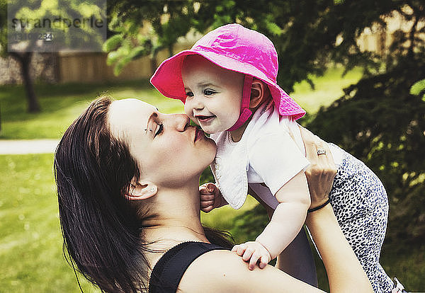 Eine junge Mutter verbringt im Sommer viel Zeit mit ihrer Tochter in einem Park und gibt ihr einen Kuss auf die Wange; Edmonton  Alberta  Kanada