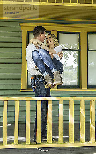 Porträt eines jungen Paares auf der Veranda eines Hauses  der junge Mann hält die junge Frau in den Armen; Bothell  Washington  Vereinigte Staaten von Amerika
